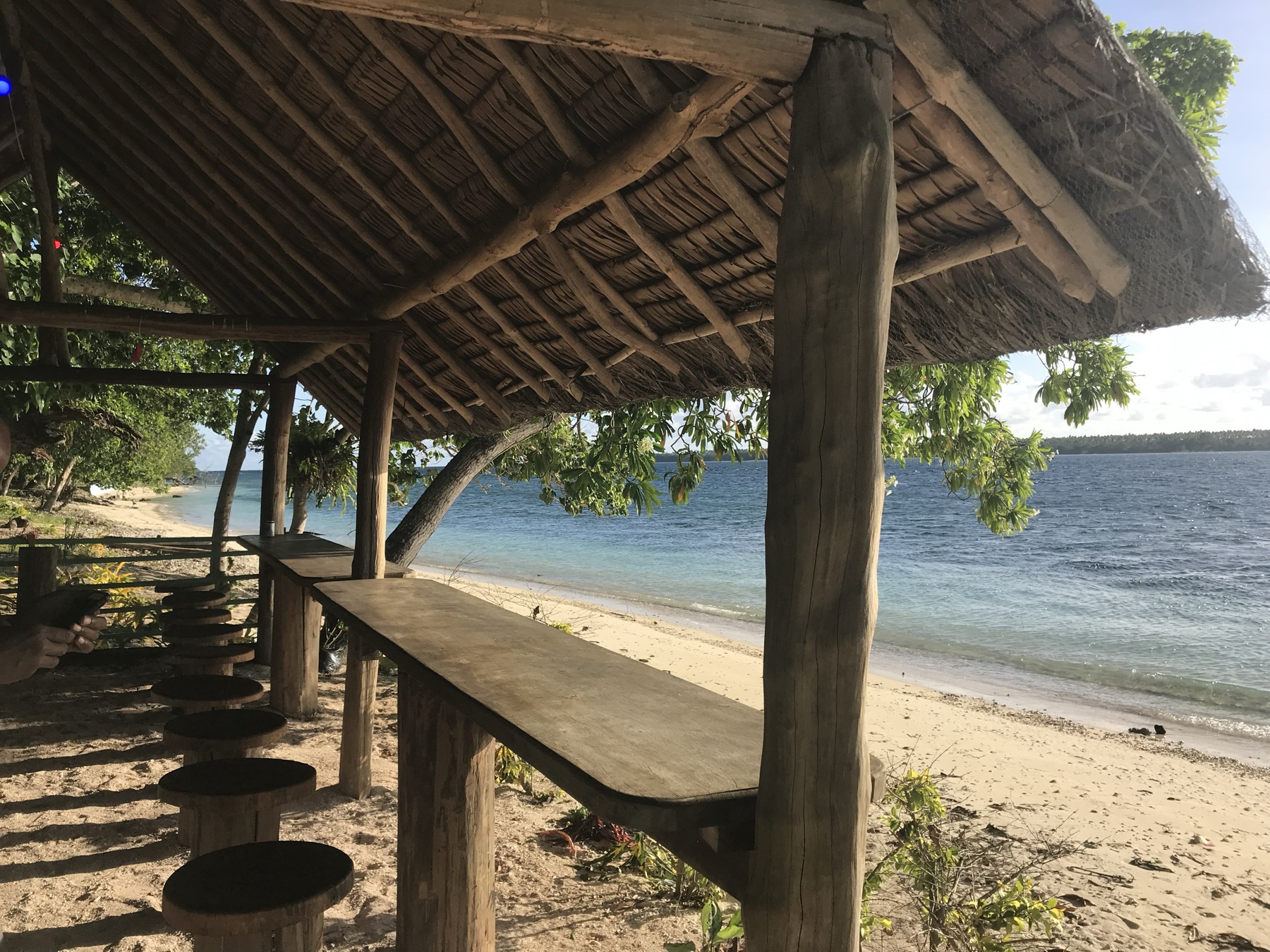 Guests enjoying drinks and island food at Lapita Beach Bar under the thatched fare, Aore Island 4