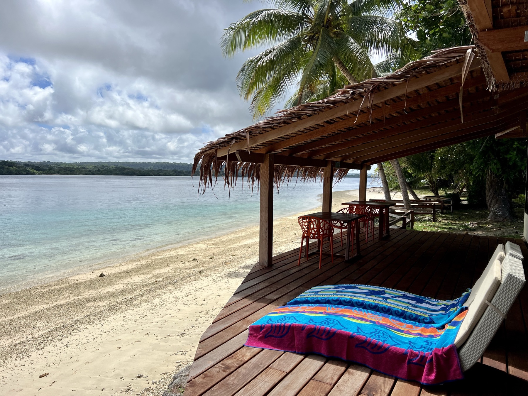 Lapita Beach Villa beachfront deck with day beds and dining under thatch, Aore Island