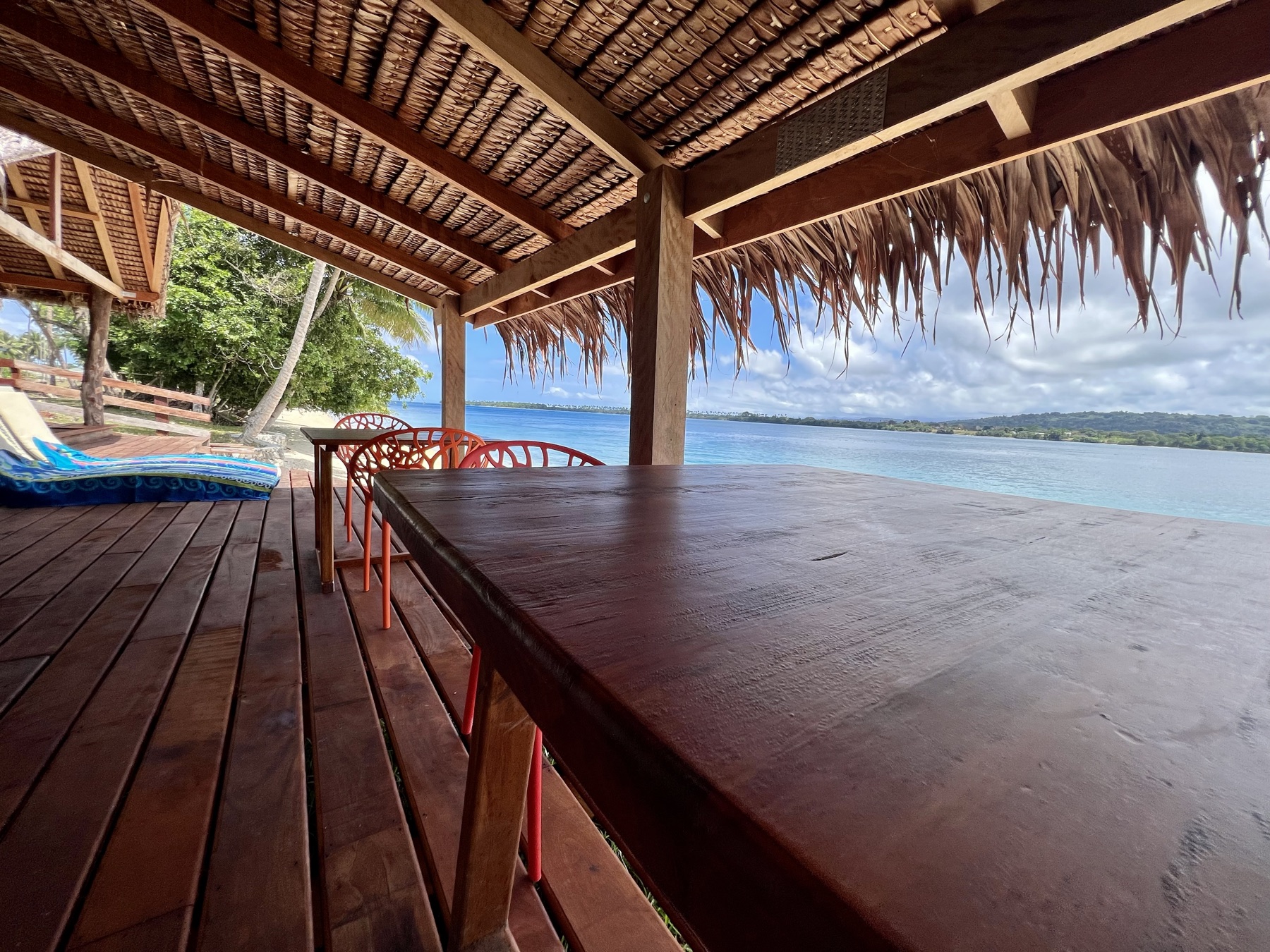 Lapita Beach Villa beachfront deck with day beds and dining under thatch, Aore Island 6